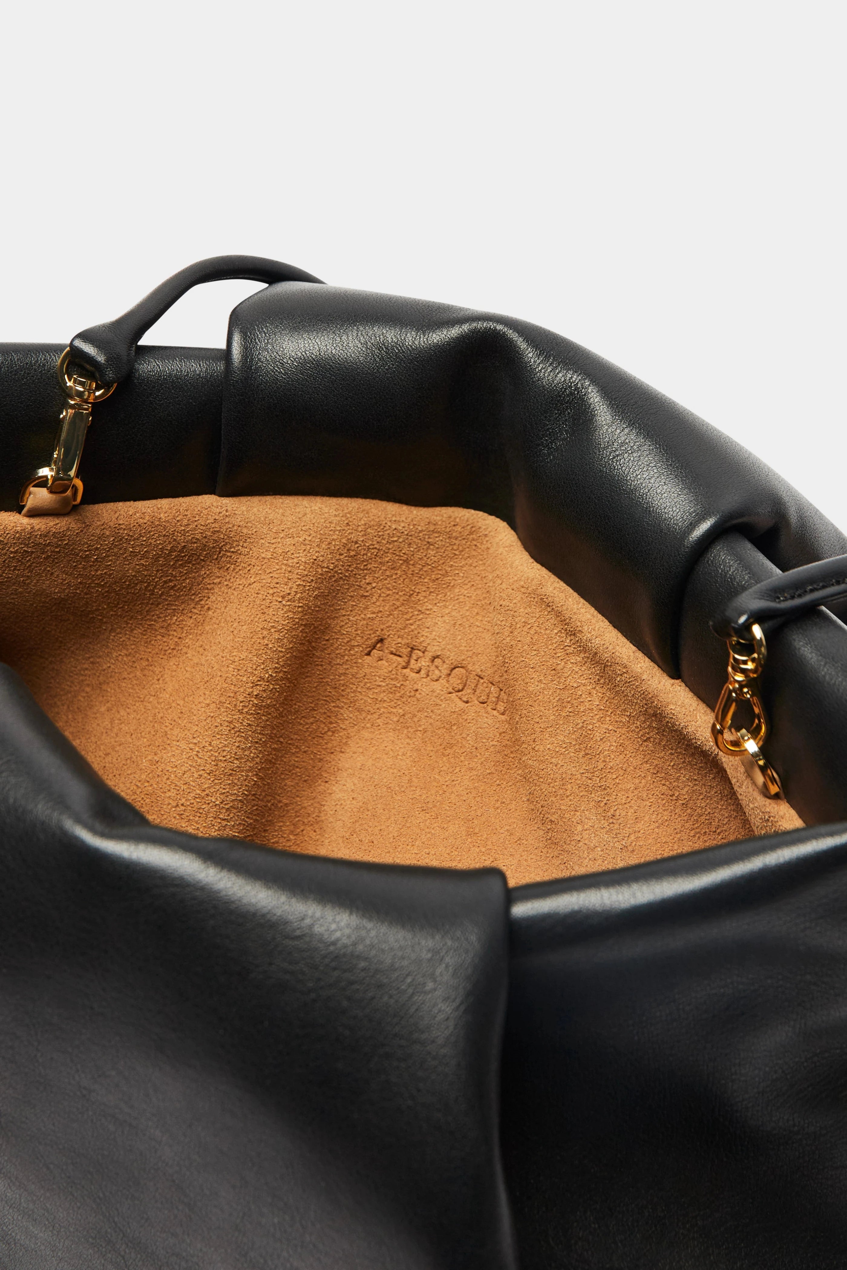 A close up image of the inside suede lining of Fold clutch bag with A-sque logo stamped in the middle.