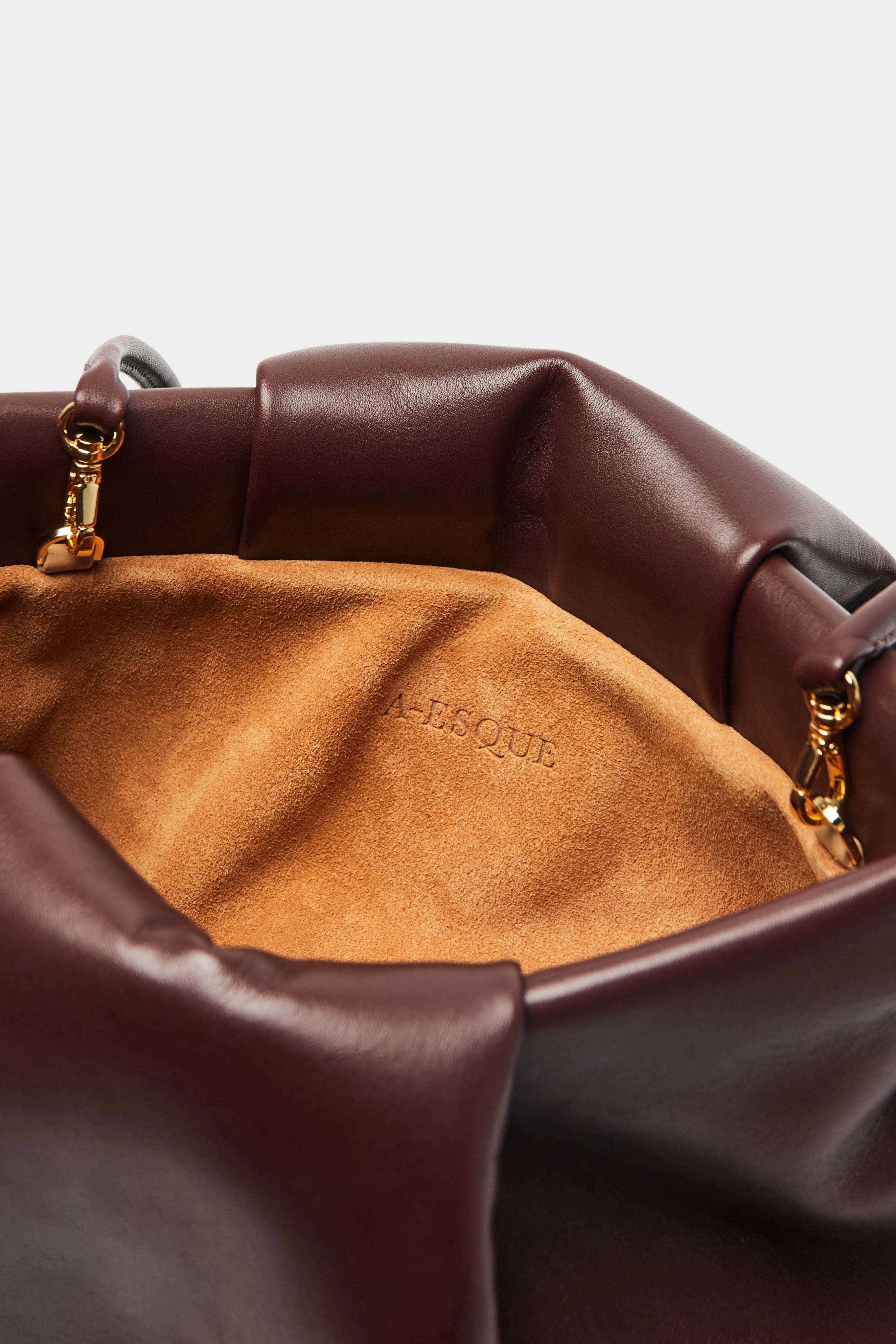 A close up image of the inside suede lining of Fold clutch bag with A-sque logo stamped in the middle.