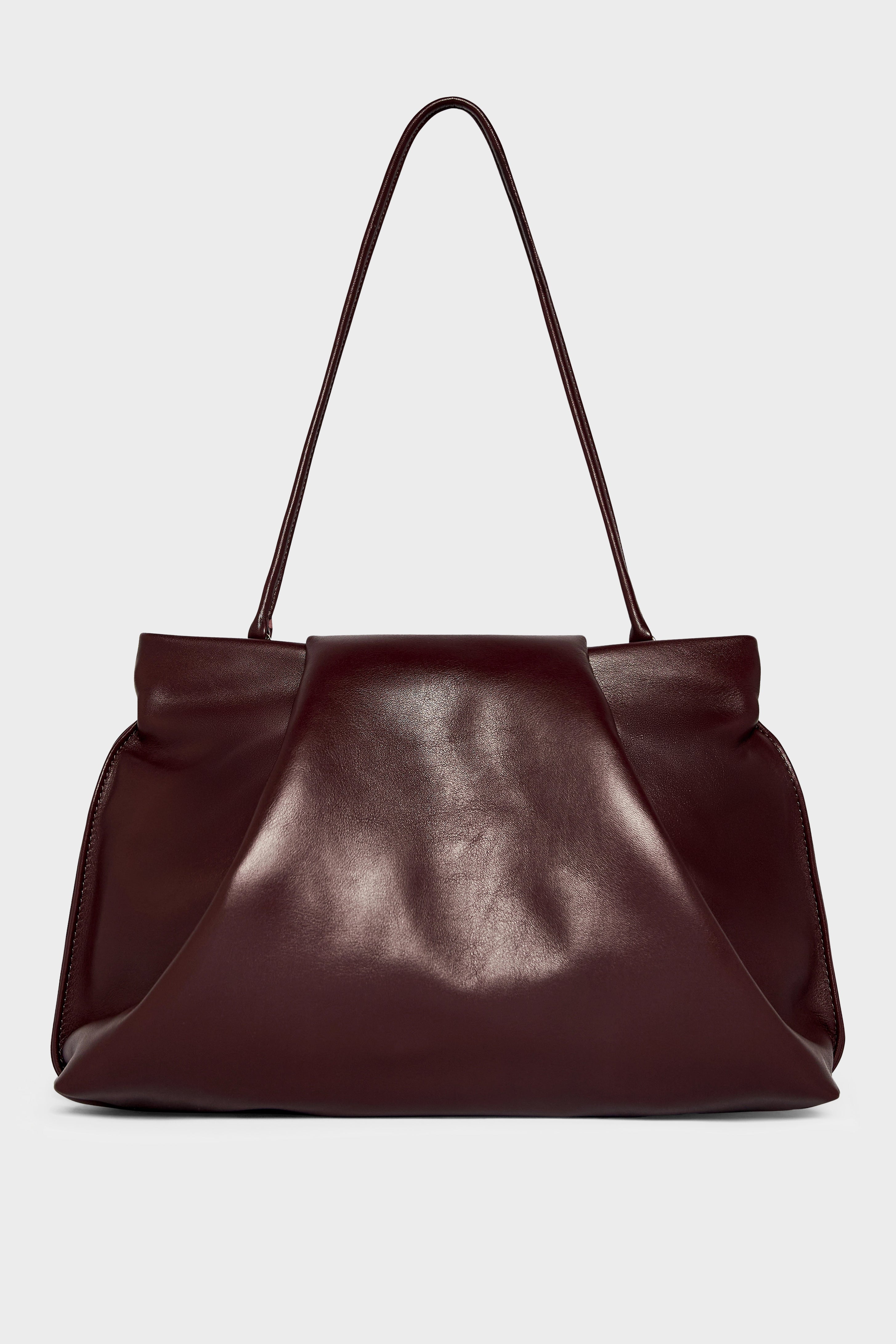 A photo of the black fold clutch bag with its handles up to function as a shoulder bag. The handbag features a modern and structured design.