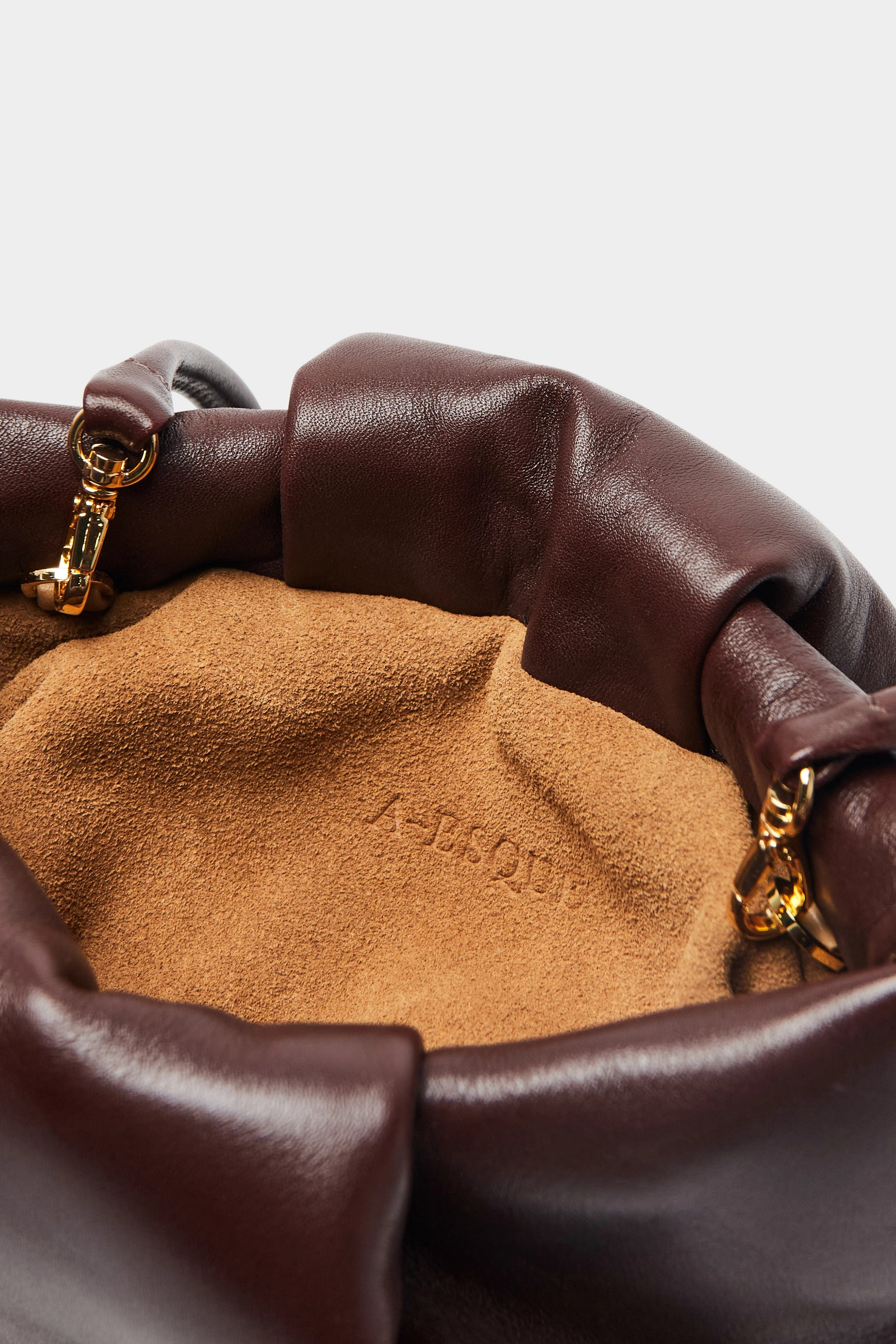 A close up image of the inside suede lining of the Fold mini clutch bag with A-sque logo stamped in the middle.