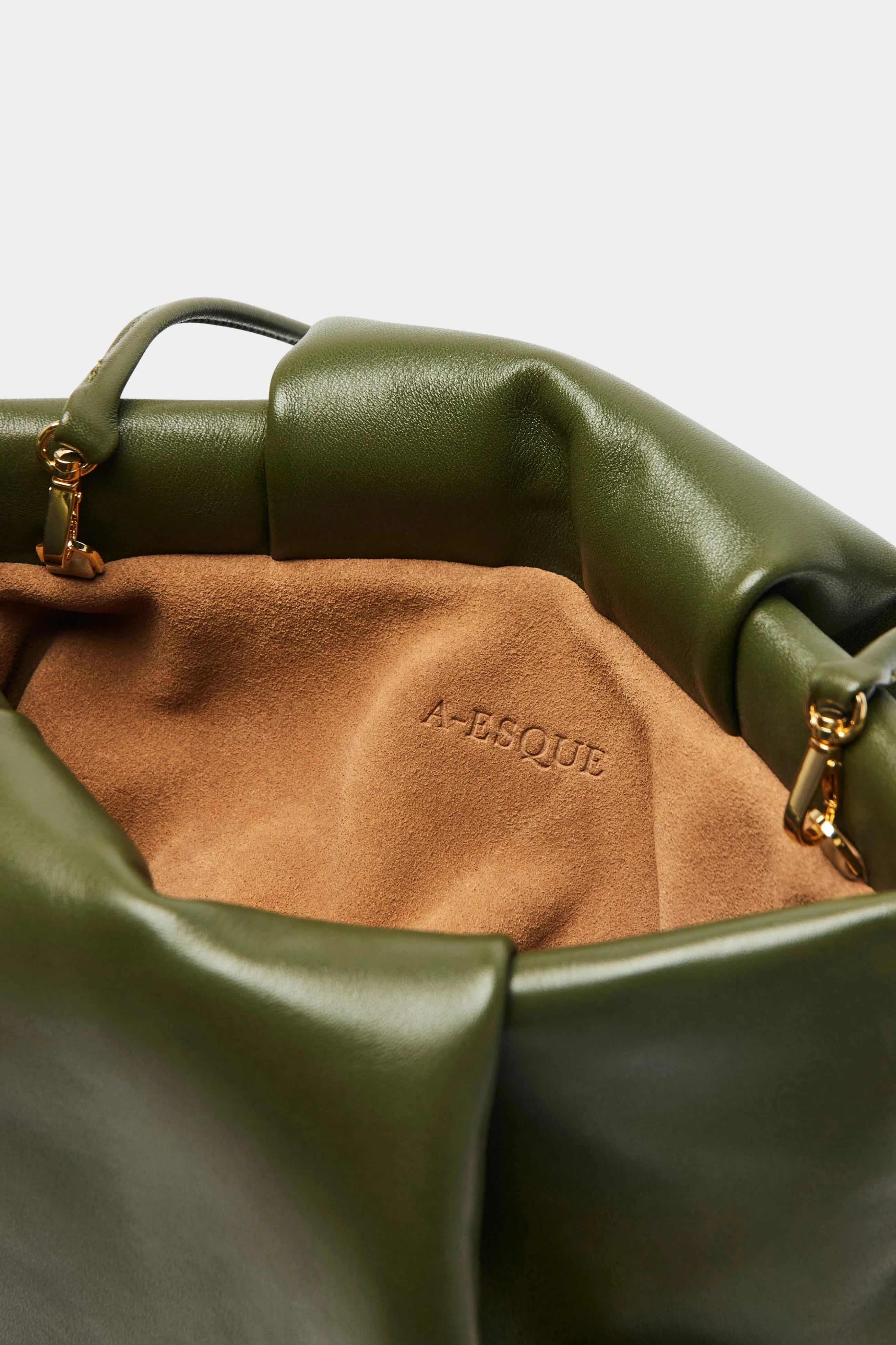 A close up image of the inside suede lining of Fold clutch bag with A-sque logo stamped in the middle.