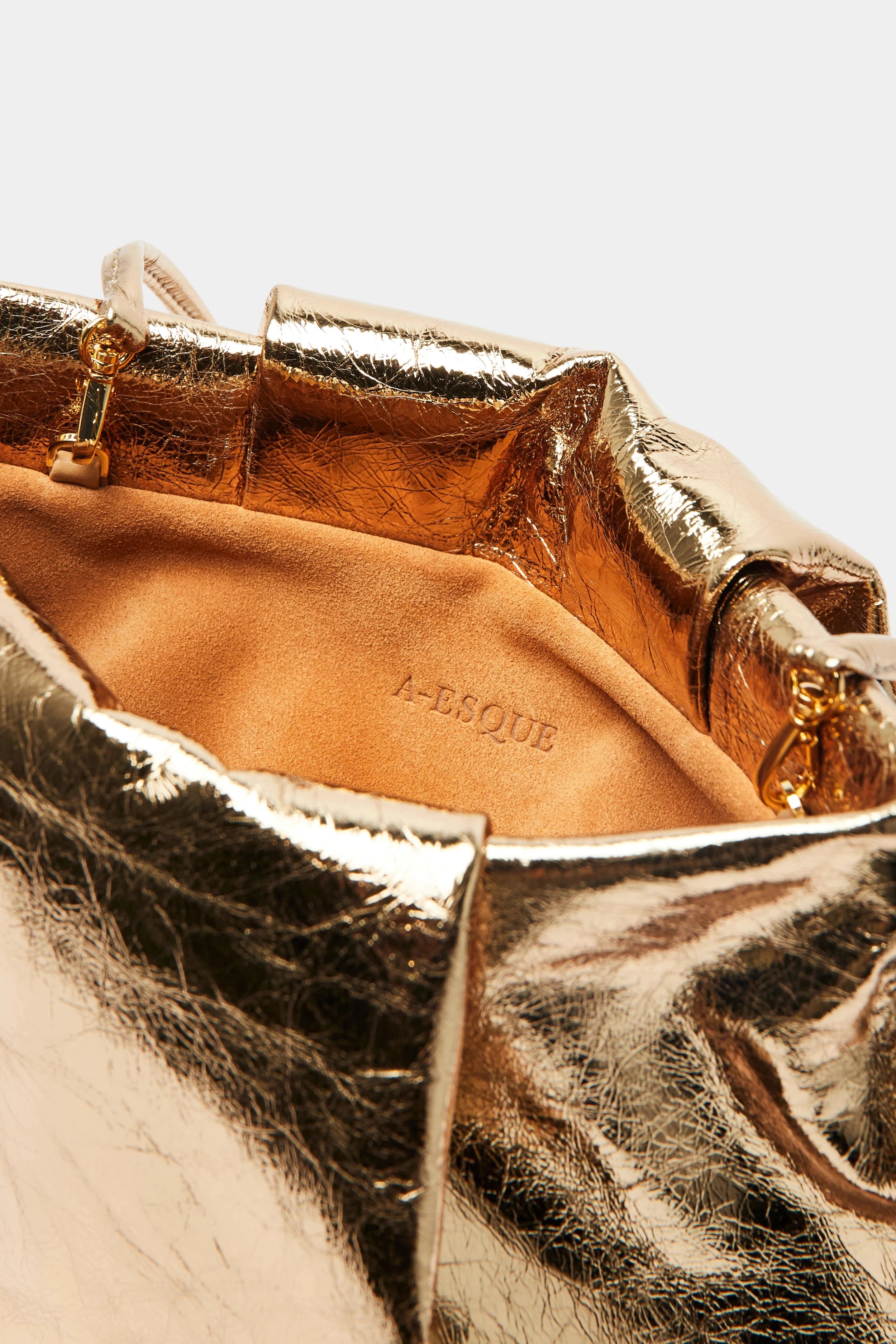 A close up image of the inside suede lining of Fold clutch bag with A-sque logo stamped in the middle.