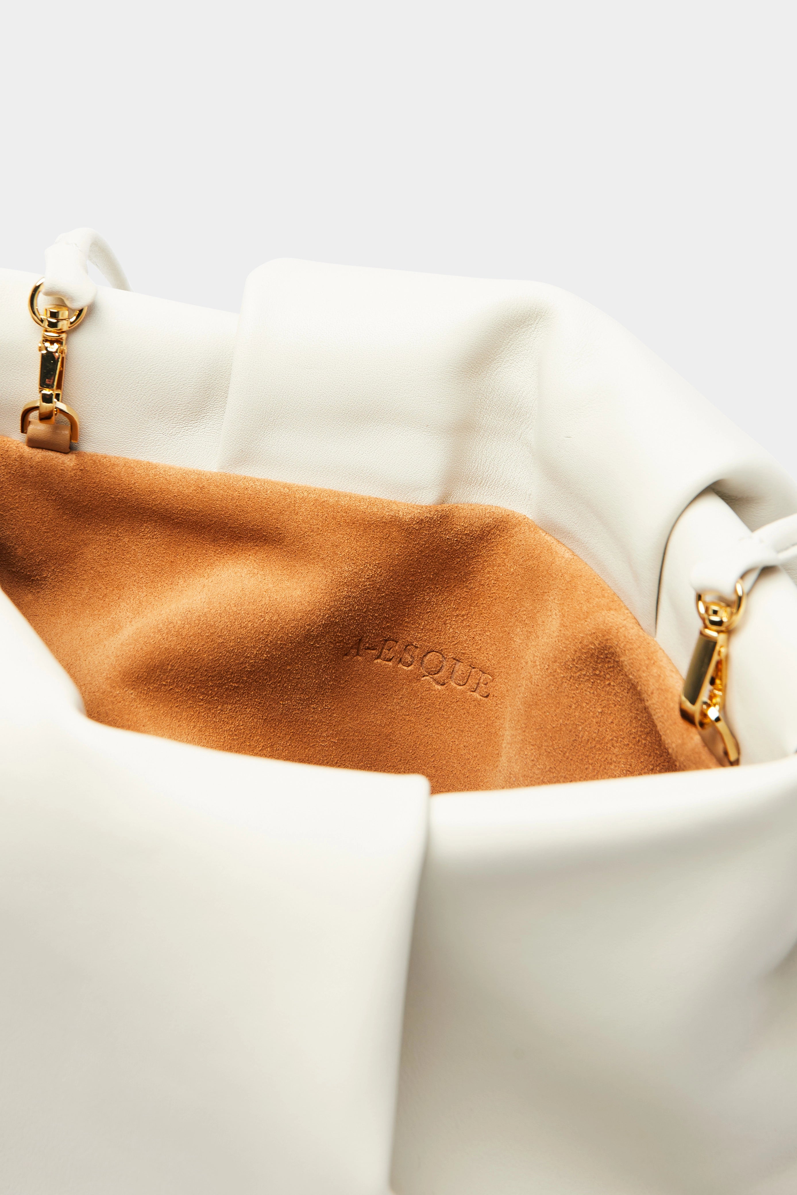 A close up image of the inside suede lining of Fold clutch bag with A-sque logo stamped in the middle.