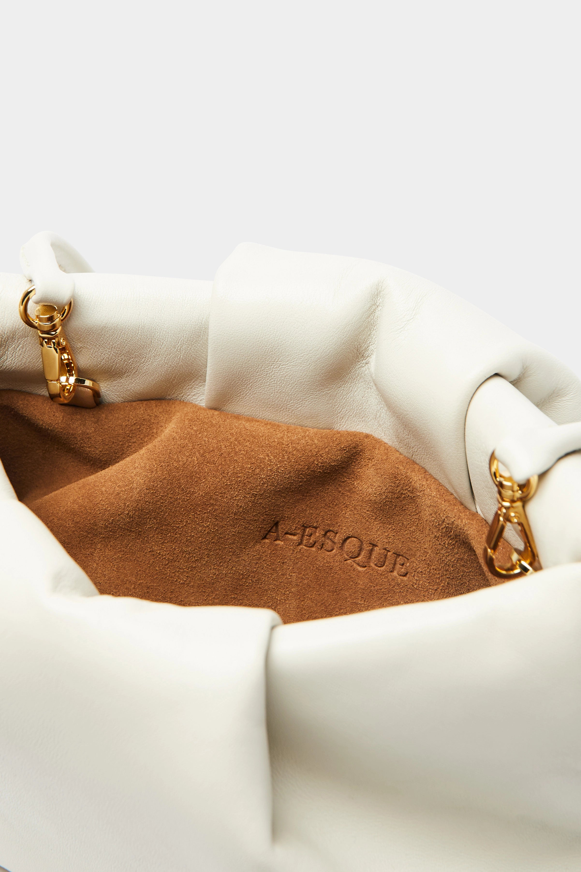 A close up image of the inside suede lining of the Fold mini clutch bag with A-sque logo stamped in the middle.