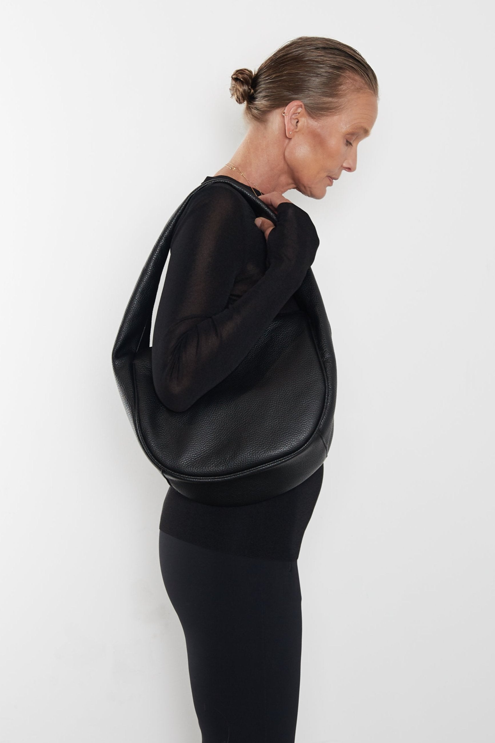 A woman carrying the Midi Halo Day shoulder bag on her shoulder. This handbag suits as a work bag or travel bag.