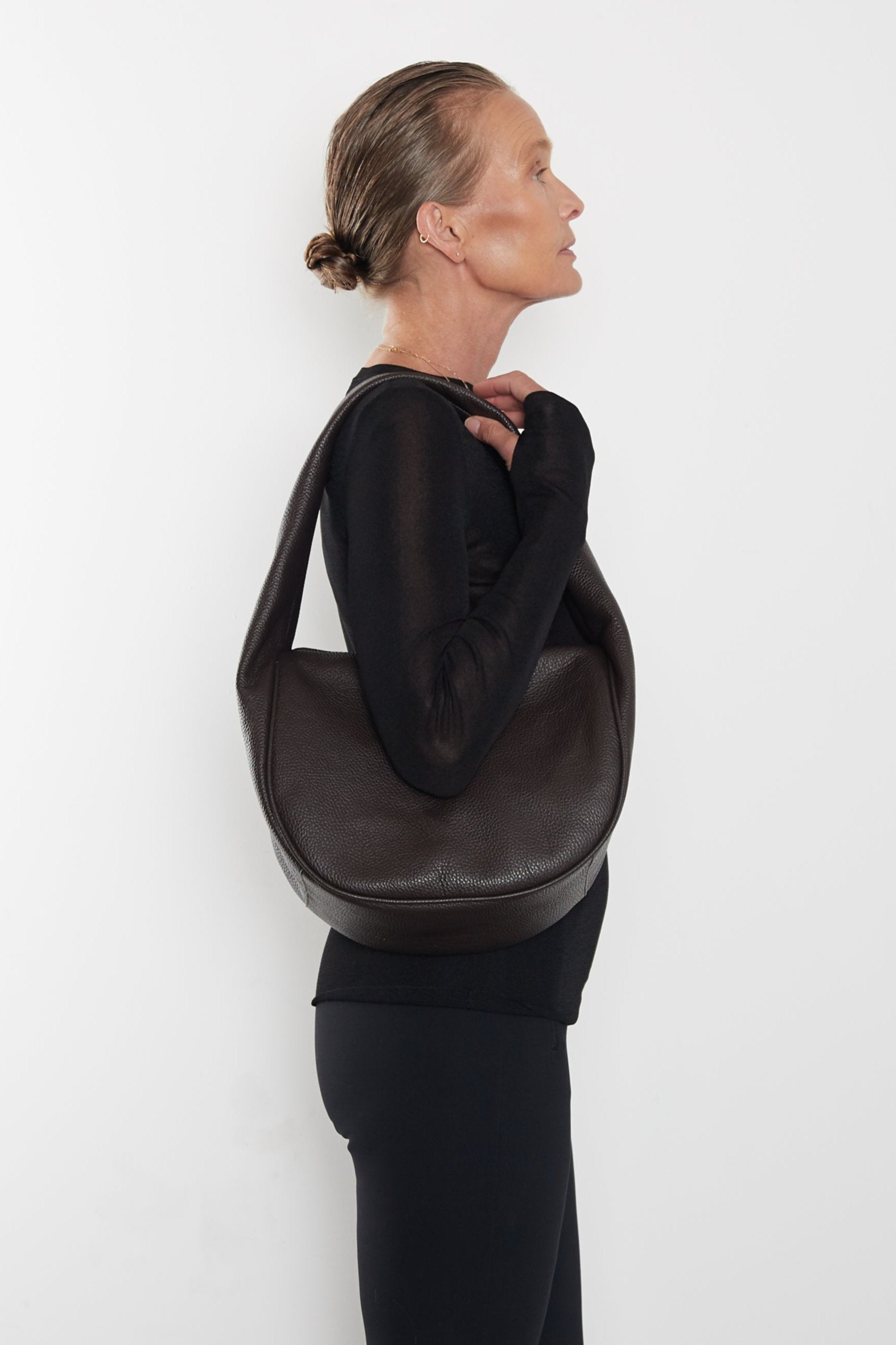 A woman carrying the Midi Halo Day shoulder bag on her shoulder. This handbag suits as a work bag or travel bag.