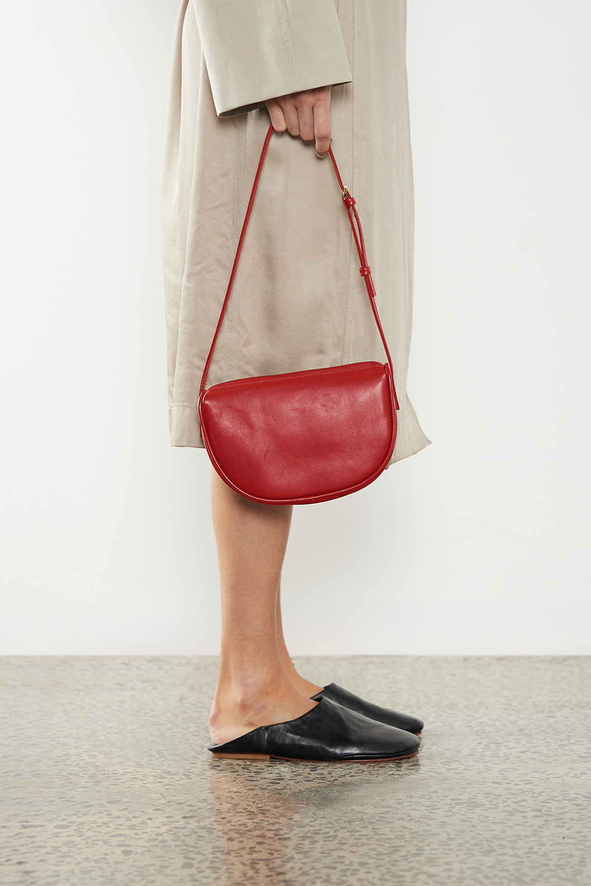 A woman carrying the mini saddle shoulder bag through its handle. It highlights a fusion of hobo and saddle bag design inspiration.