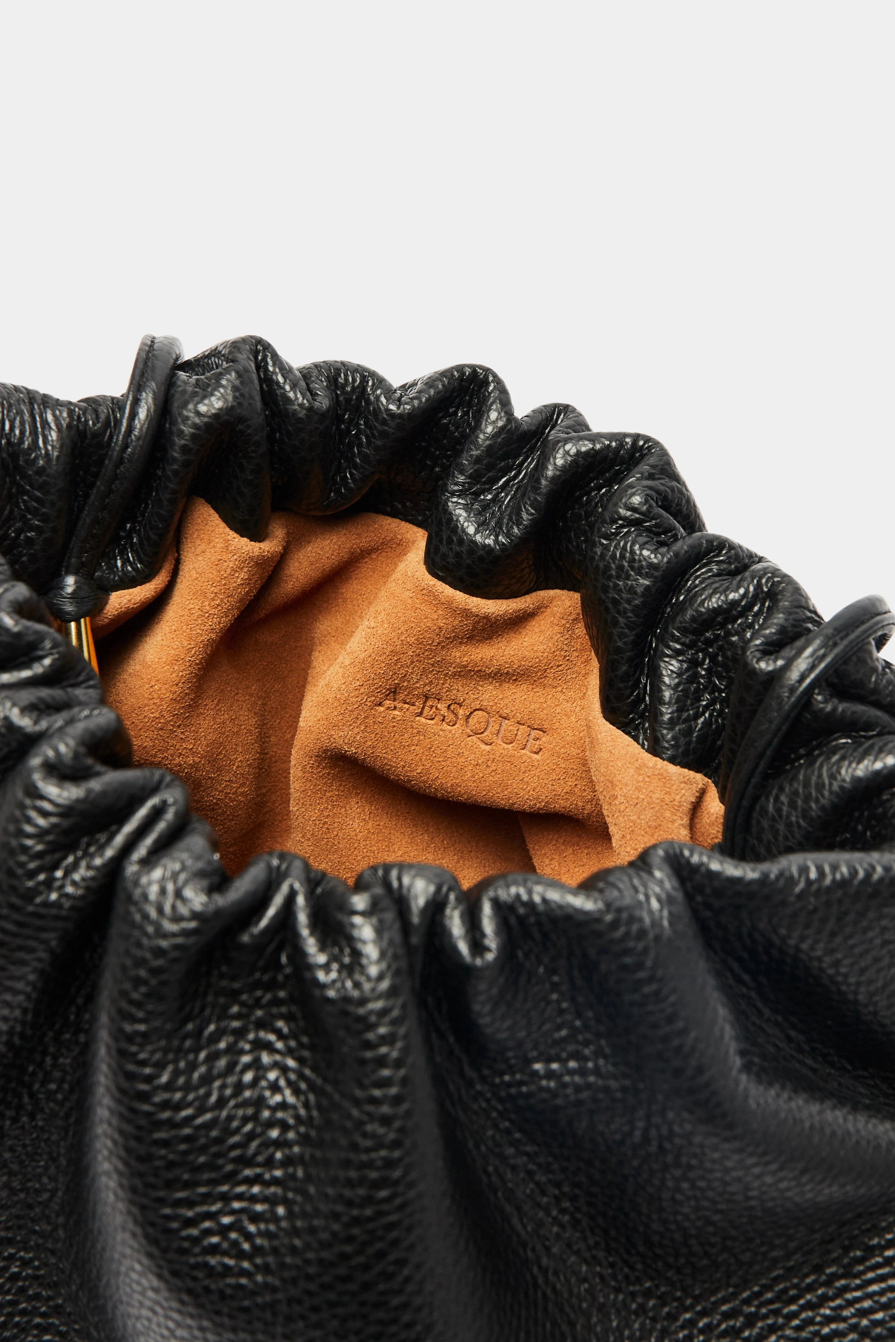 Puffa clutch crossbody bag has a suede interior lining with an A-esque logo stamped in the middle.