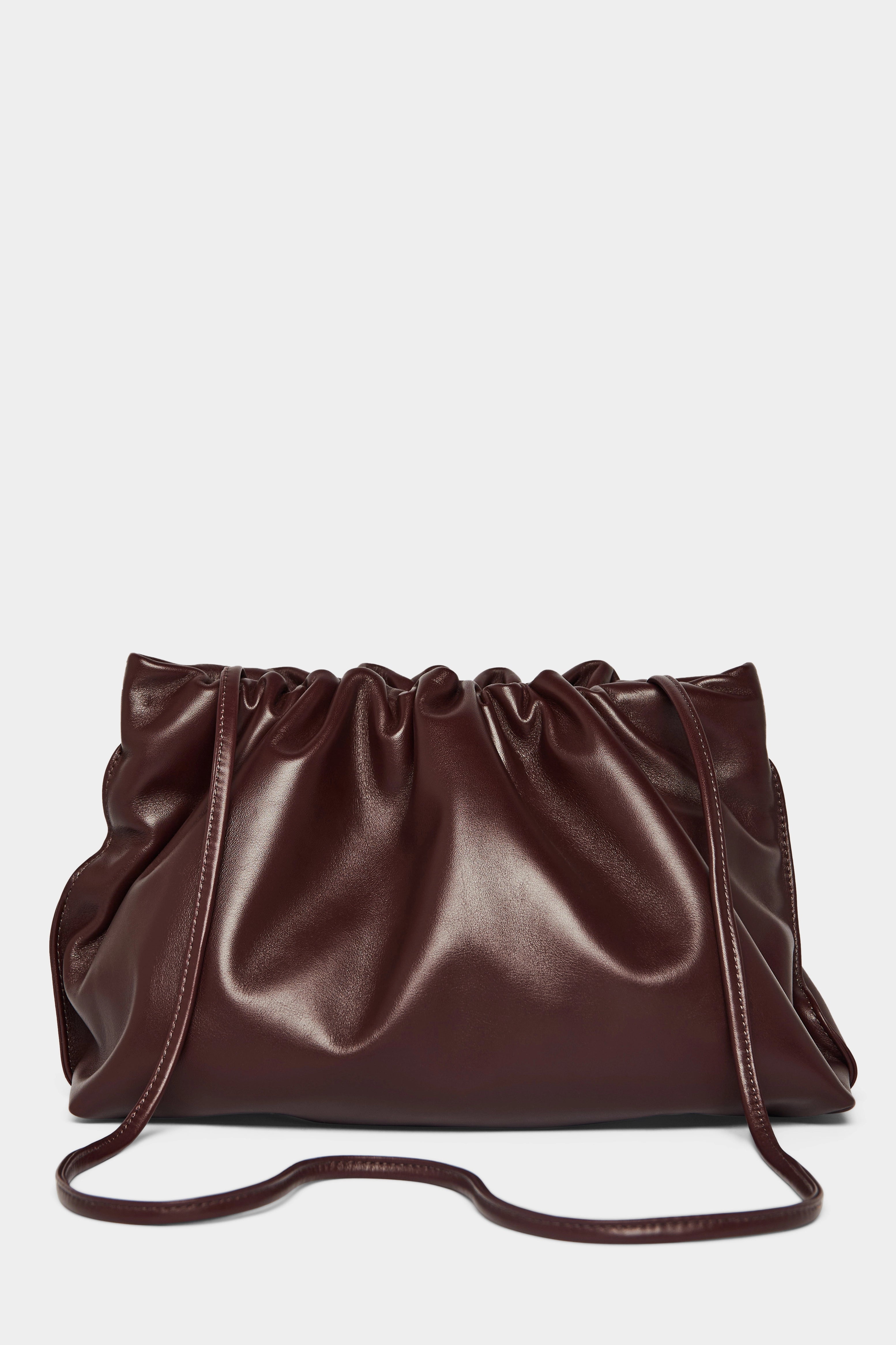 A burgundy clutch bag with a long removable shoulder strap. The handbag can also be worn handheld or a crossbody bag.