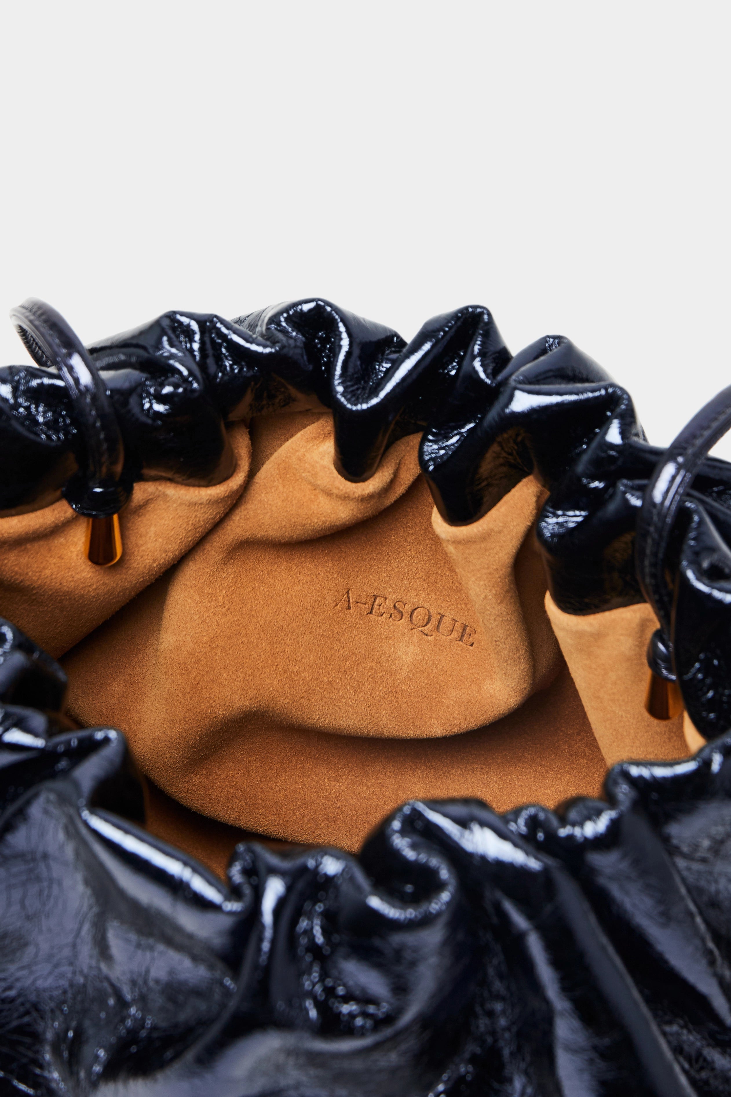 Puffa clutch crossbody bag has a suede interior lining with an A-esque logo stamped in the middle.