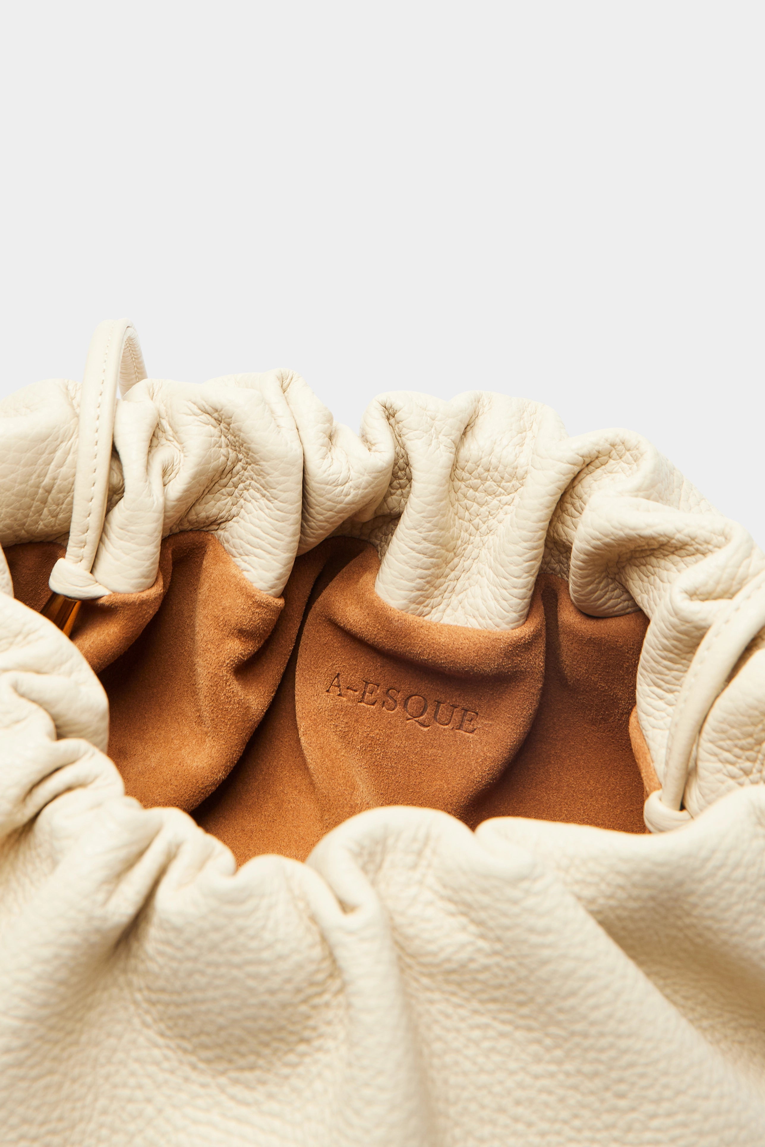 Puffa clutch crossbody bag has a suede interior lining with an A-esque logo stamped in the middle.