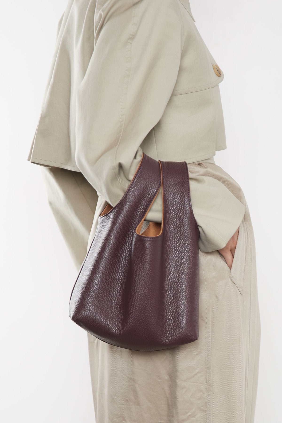 A woman carrying the small reversible tote bag slung in the crook of the arm. This mini bag works well as an everyday purse.