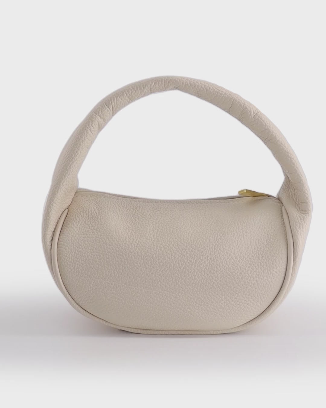 A rotating video of the mini bag featuring its U-shaped body connected by a single handle and a snippet of the bag's interior.