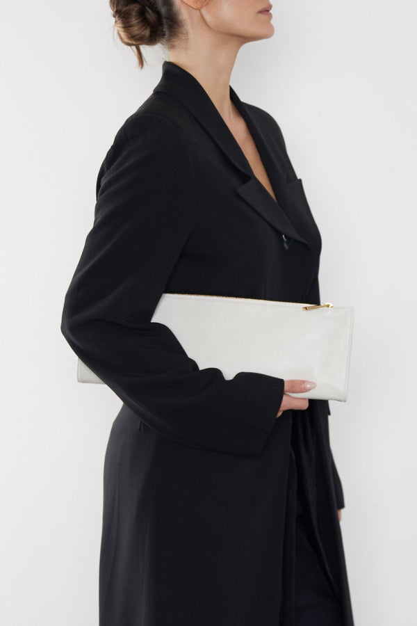 A woman carrying the red slimline clutch pouch. The clutch is folded and looks like a long wallet. It's suited as a party clutch or a casual pouch or purse.