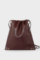 A burgundy backpack with a draw closure. The backpack has a versatile design and can be worn as a shoulder bag or crossbody bag for men and women.