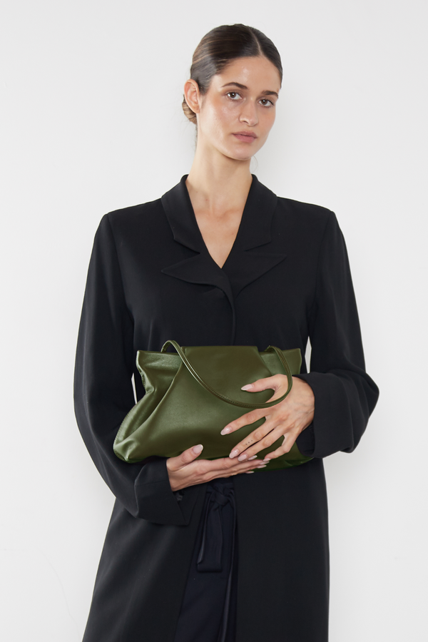 A woman carrying the khaki fold clutch bag handheld. The bag can carry enough daily essentials and is suited as a work bag or a purse clutch for events.