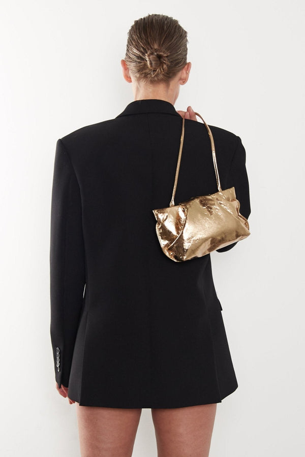 A woman carrying the fold mini clutch bag with its removable strap hanging. This handbag can be used both as a shoulder bag or a purse clutch.