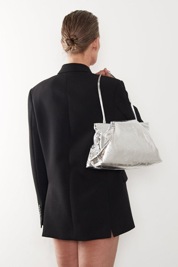 A woman carrying the strap of the fold clutch slung on her shoulder. The bag can be worn handheld or as a shoulder bag.