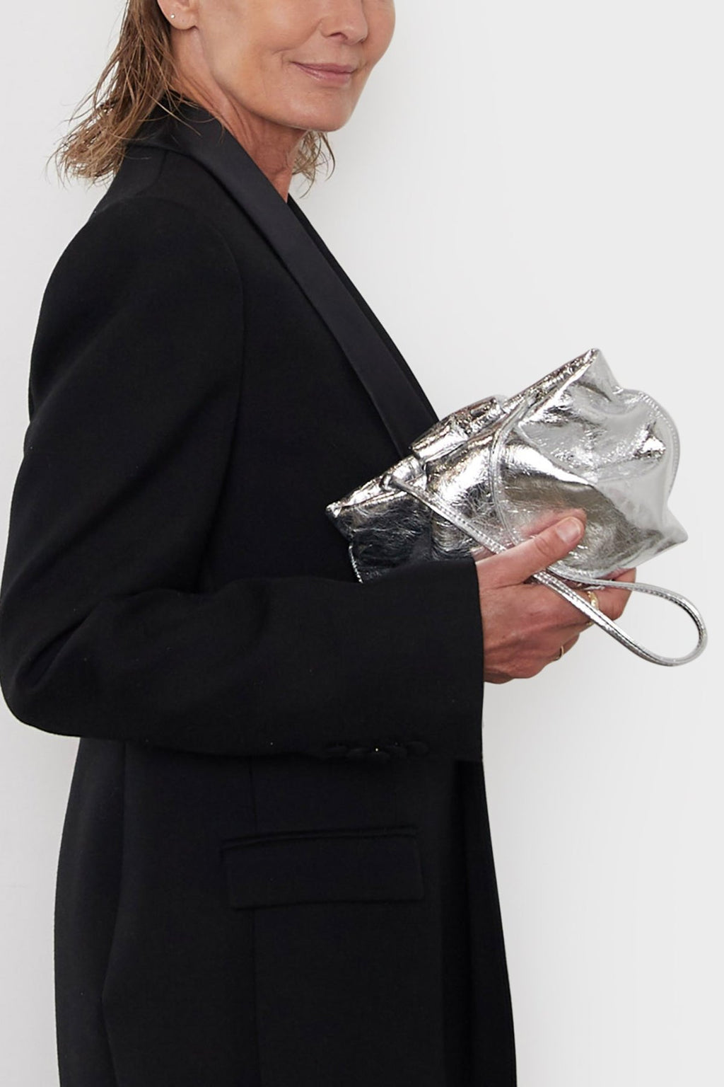 A woman carrying the Fold  mini clutch bag. The handbag has a modern design suited as a party clutch or purse for events.