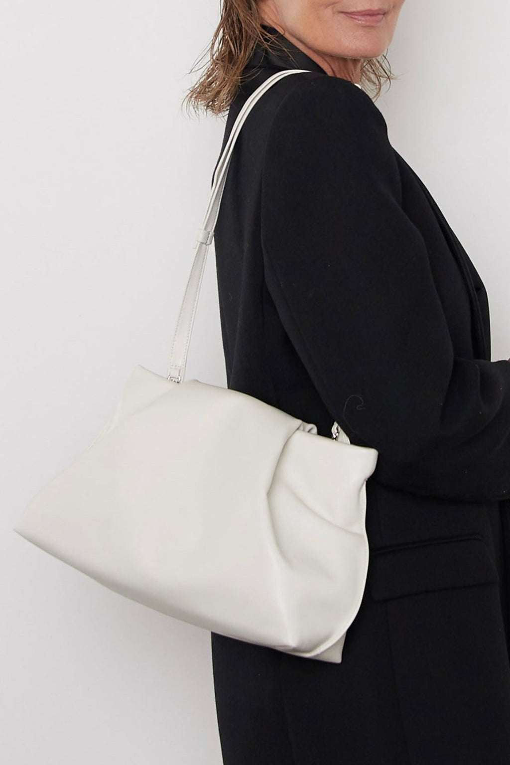 A woman wearing the fold clutch as a shoulder bag.