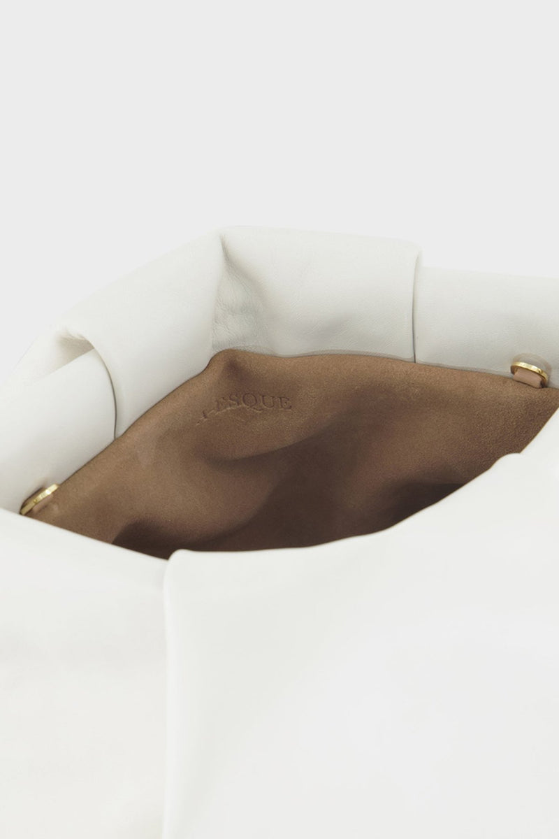 A close-up image of the inside brown suede lining of Fold clutch bag with A-sque logo stamped in the middle.