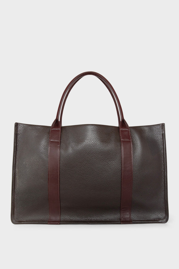 A large dark brown tote bag with a rectangular body. It has a wide top with a magnetic closure. The bag has 2 handles to be carried handheld or as a shoulder bag.