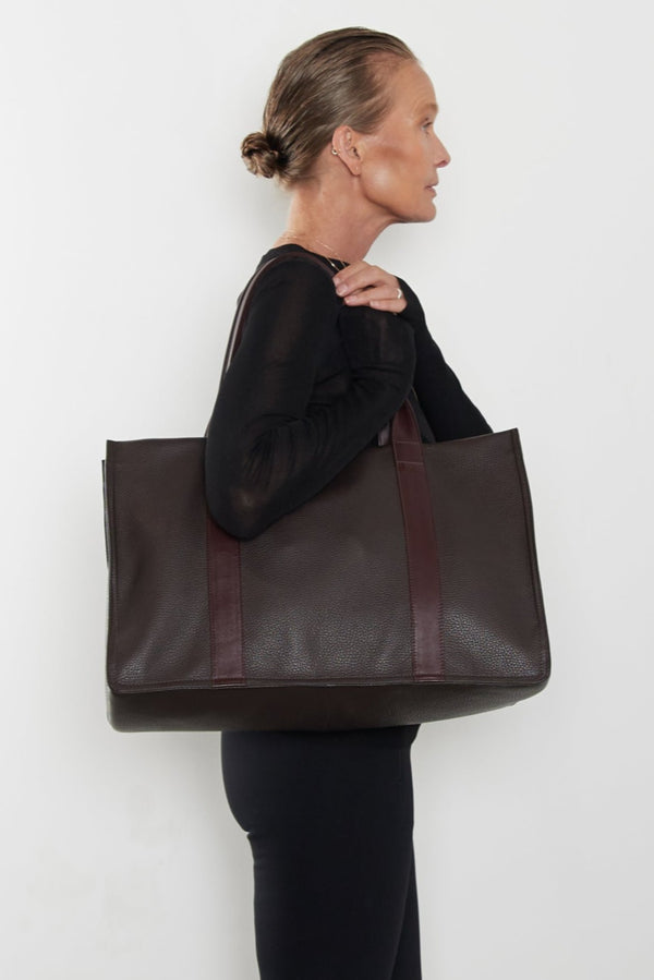 An image of a woman carrying the Grocer tote as a shoulder bag. The bag can be used as a work bag or a travel bag.