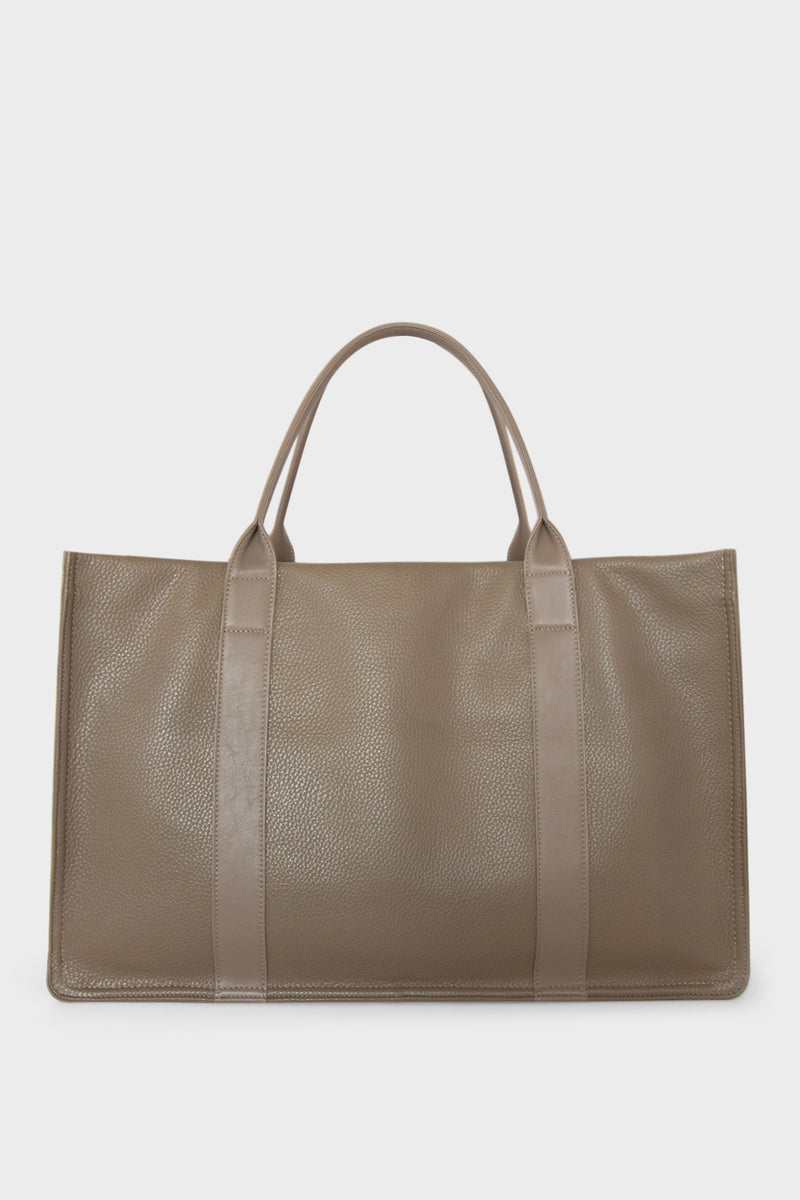 A large grey tote bag with a rectangular body. It has a wide top with a magnetic closure. The bag has 2 handles to be carried handheld or as a shoulder bag.