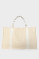 A large white tote bag with a rectangular body. It has a wide top with a magnetic closure. The bag has 2 handles to be carried handheld or as a shoulder bag.