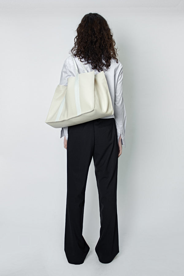 A woman carrying the Grocer tote bag in her arms. This tote bag is large for everyday use.