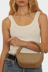 A woman carrying the Mini Halo bag in the crook of her arm. It shows the front angle of the handbag with its petite structured body. 