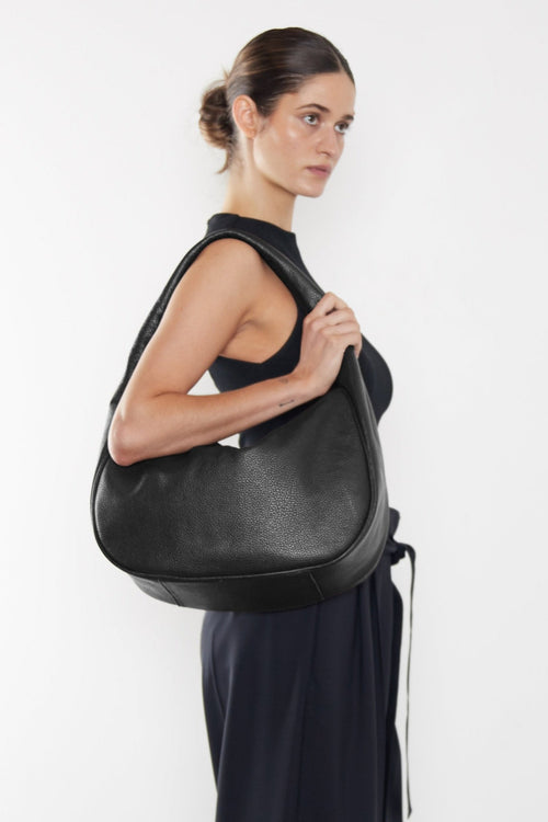 A woman carrying the Halo Day shoulder bag on her shoulder. This handbag suits as a work bag or travel bag.