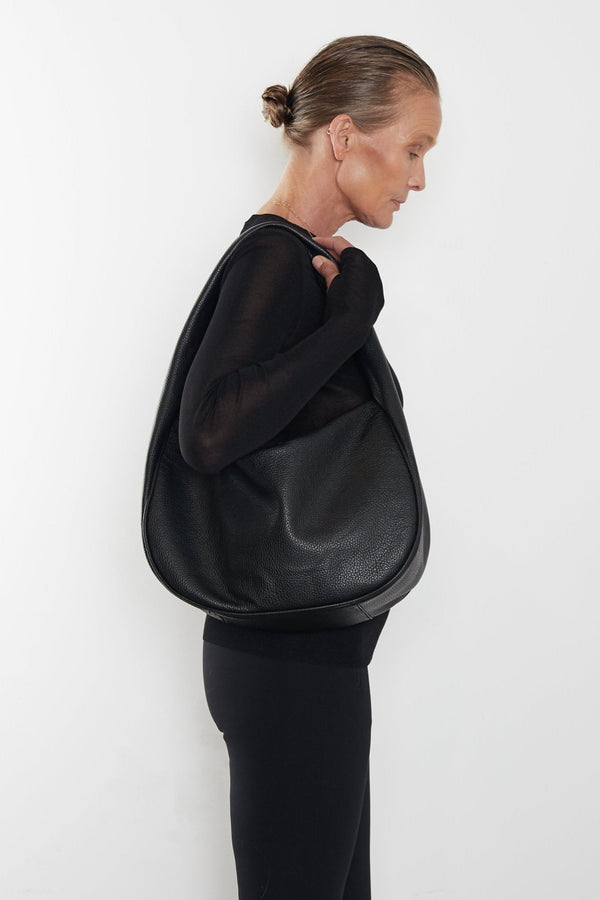 A woman carrying the Halo Day shoulder bag on her shoulder. This handbag suits as a work bag or travel bag. 