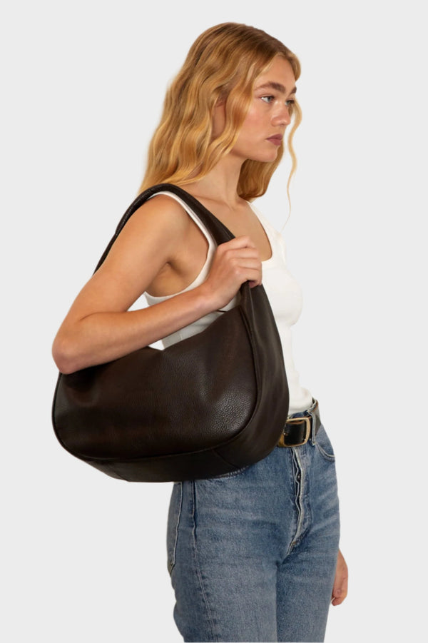 A woman carrying the halo day shoulder bag. The bag is large and great as a day bag.