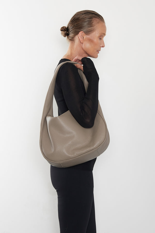 A woman carrying the Halo Day shoulder bag on her shoulder. This handbag suits as a work bag or travel bag. 