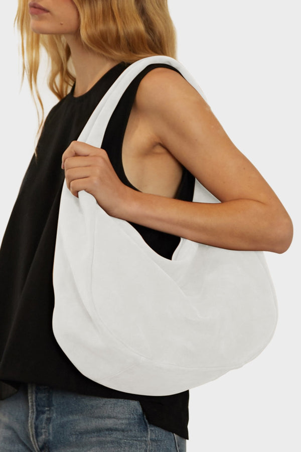 An angled image of halo day shoulder bag. It shows the front of the bag with its fine hand stitching, hobo inspired design and structured body.