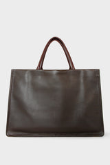 A large dark brown tote bag with a rectangular body. It has a wide top with a magnetic closure. The bag has 2 handles to be carried handheld or as a shoulder bag.