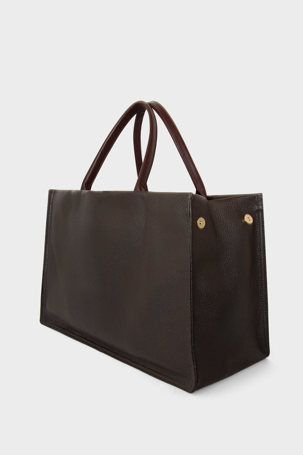 An image of the Junior Suite Tote Bag's magnetic closure. With an open-top design, the handbag can be closed through magnets on both sides.