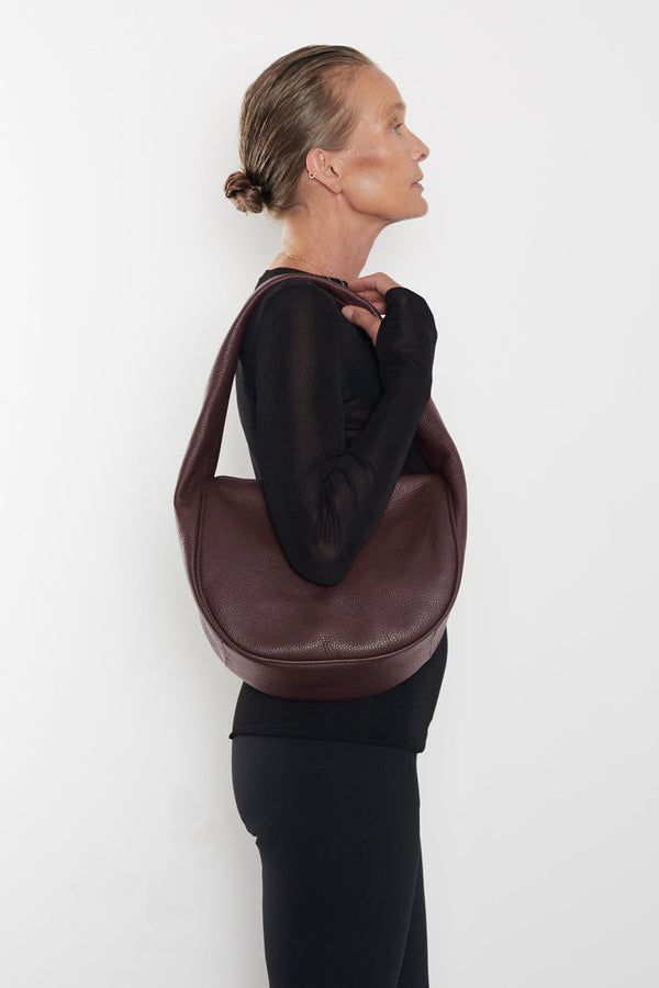 A woman carrying the Midi Halo Day shoulder bag on her shoulder. This handbag suits as a work bag or travel bag. 