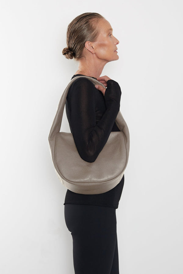 A woman carrying the Midi Halo Day shoulder bag on her shoulder. This handbag suits as a work bag or travel bag. 