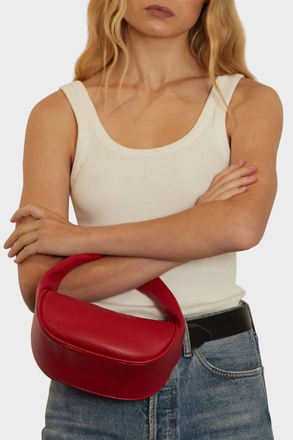 A woman carrying the Halo Mini bag in the crook of her arm. It shows the front angle of the handbag with its petite structured body. 