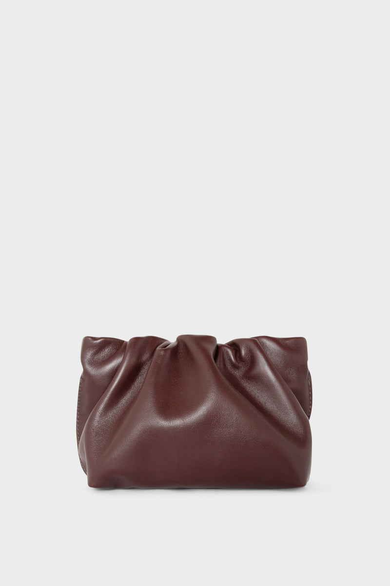 A burgundy mini clutch bag made of smooth Italian leather. This mini bag has a long removable strap and can also be worn as a crossbody bag.