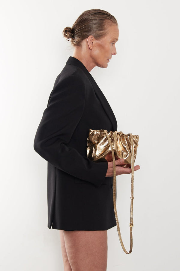 A woman carrying the puffa mini bag. This handbag has a structured minimalist design to be carried as a purse or a crossbody bag with its removable strap.