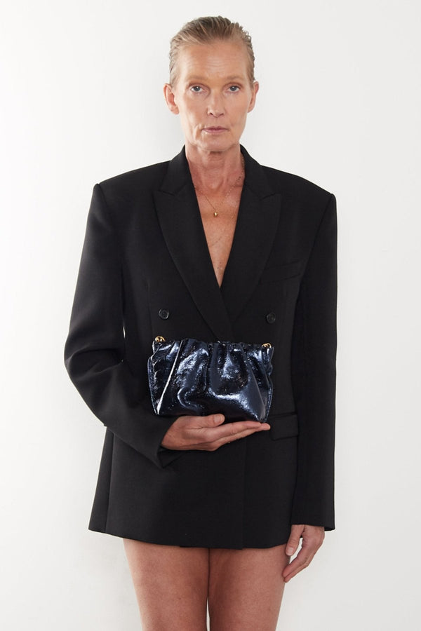 A woman carrying the metallic midnight mini Puffa clutch bag. This mini bag has a modern design suited as a party clutch purse.