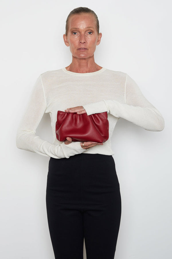 A woman carrying the red mini Puffa clutch bag. This mini bag has a modern design suited as a party clutch purse.