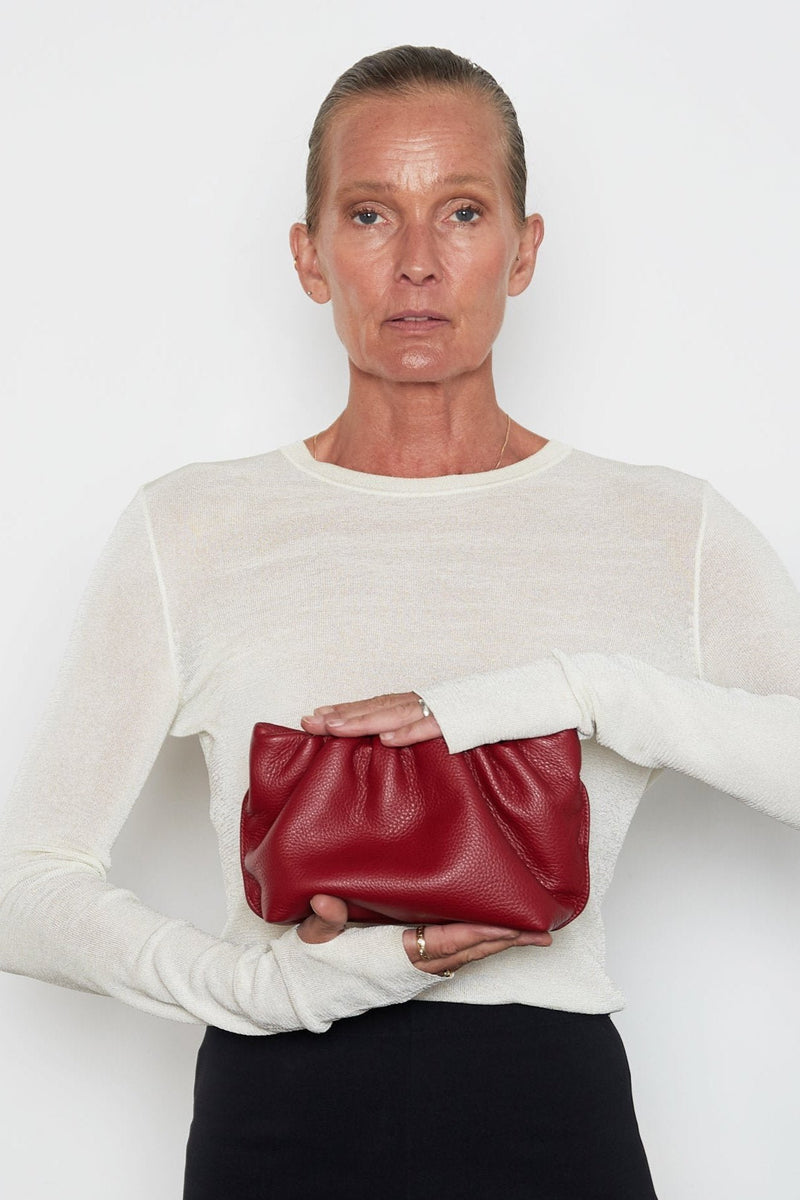 A woman carrying the red mini Puffa clutch bag. This mini bag has a modern design suited as a party clutch purse.