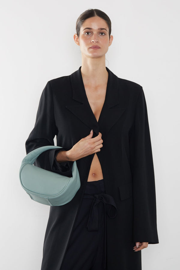 A woman carrying the Halo Mini bag in the crook of her arm. It shows the front angle of the handbag with its petite structured body. 