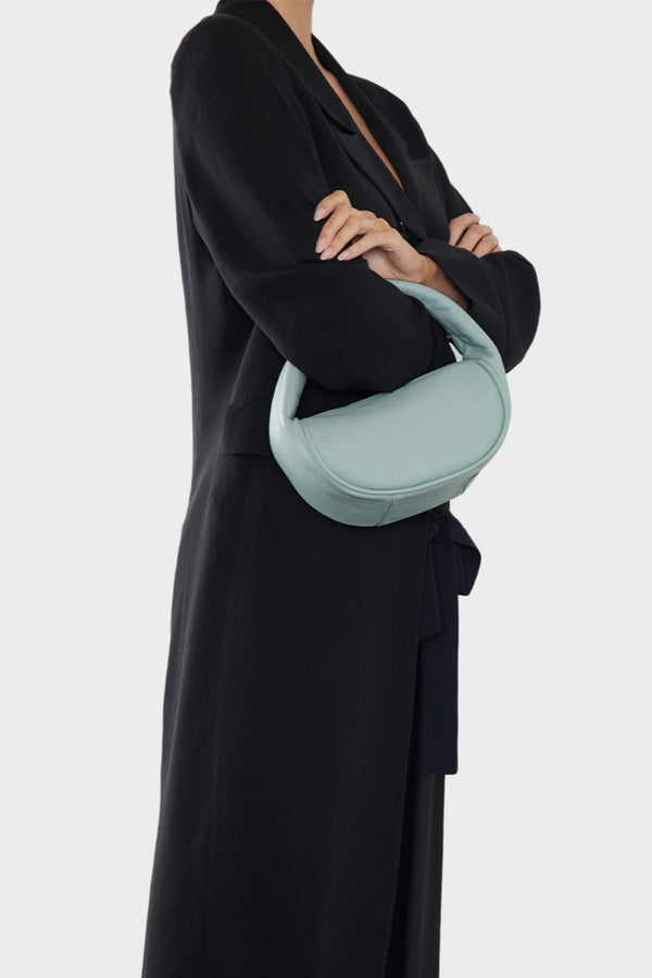 A woman carrying the mini halo bag in the crook her arm. This handbag can be carried as a clutch or a purse during parties and events.