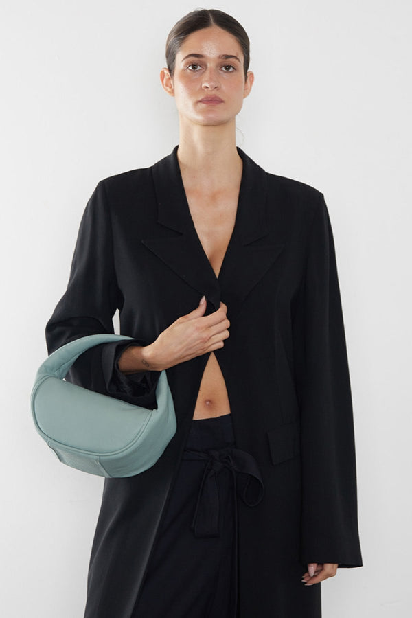 A woman carrying the Mini Halo bag in the crook of the arm. It shows the front angle of the handbag with its petite structured body.