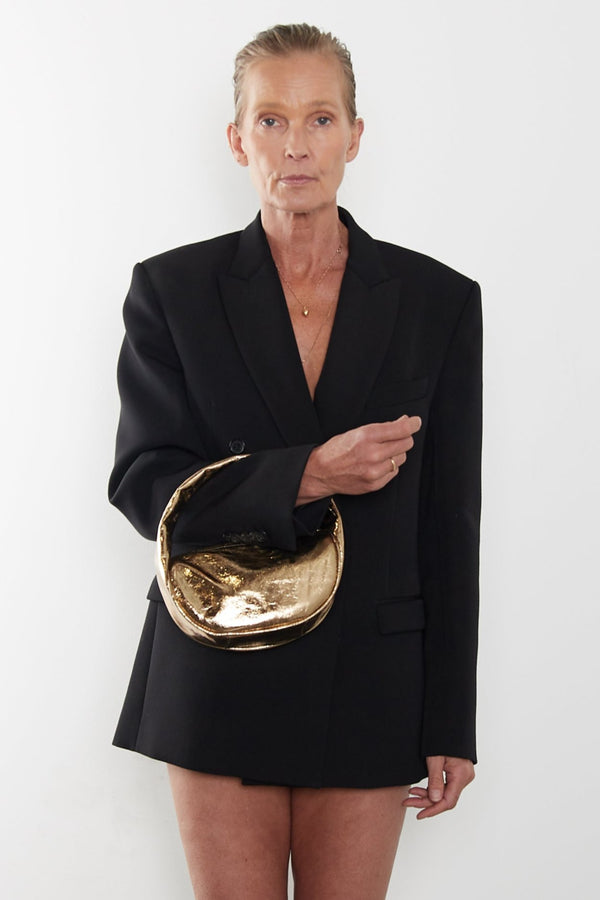 A woman carrying the Mini Halo bag in the crook of her arm. It shows the front angle of the handbag with its petite structured body.